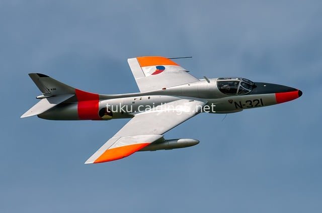 Hawker Hunter Fighter Soaring in the Blue Sky with Silver-Orange Livery
