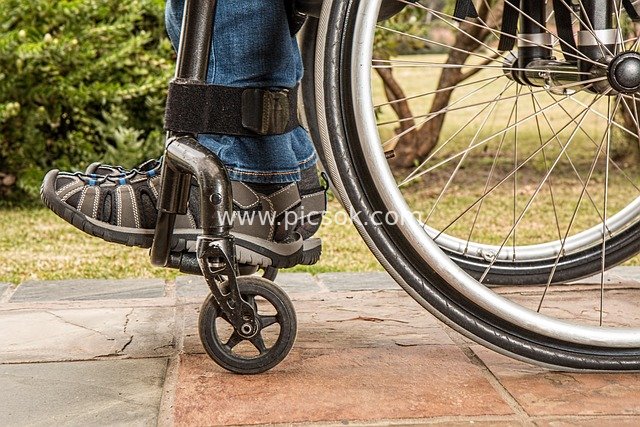 Actual Close-up Photo of a Person with a Disability Using a Wheelchair in an Outdoor Rehabilitation Assistance Scene