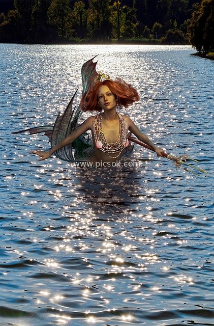 Fantasy Scene of a Red-Haired Mermaid Holding a Trident Under Shimmering Lake Light