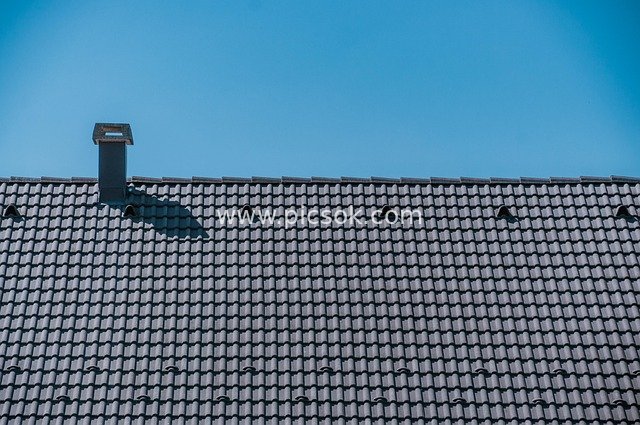 Residential Landscape with Dark Tiled Roof and Clear Blue Sky