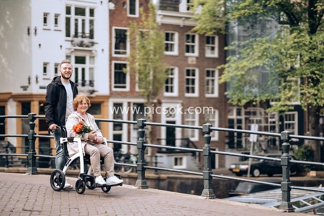 Man Accompanying Woman with a Walker Strolling by European-style Bridge