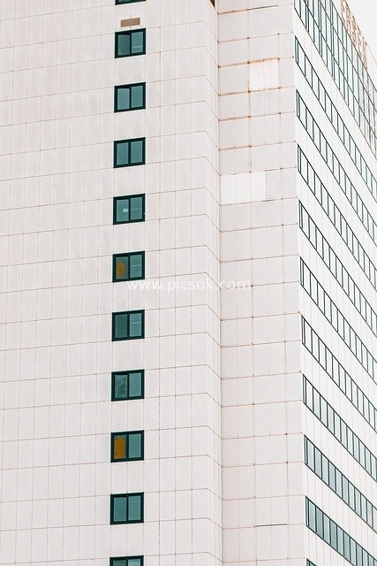 Exterior of Modern High-Rise Building: Symmetrical Hospital Windows and White Curtain Wall