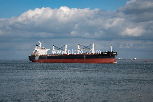 Large Cargo Ship Sailing on Open Sea Under Blue Sky and White Clouds - Maritime Scene