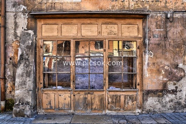 Vintage Worn Wooden Door, Weathered Walls, and Windowed Entrance of an Old Building
