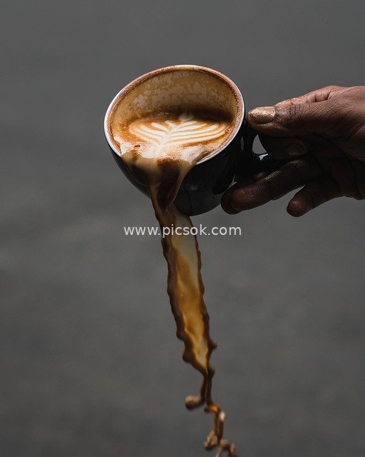 Holding a Black Cup of Latte Art: The Beautiful Moment of Coffee Spilling