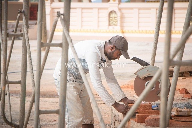 Construction Worker Cutting Red Bricks On-Site: Real Shot of Construction Scene
