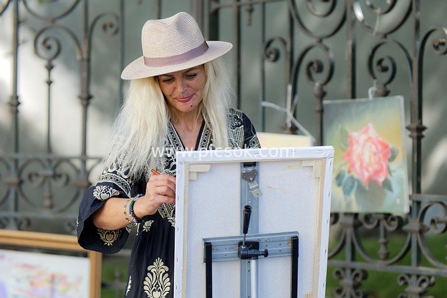 Scene of a Female Painter Creating an Oil Painting on the Street While Wearing a Hat