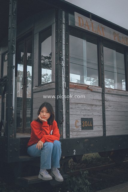 A Girl in a Red Hoodie Waiting for a Trip Beside a Vintage Train