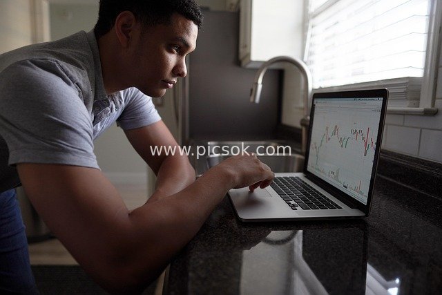Financial Investor Focused on Stock Charts in the Kitchen