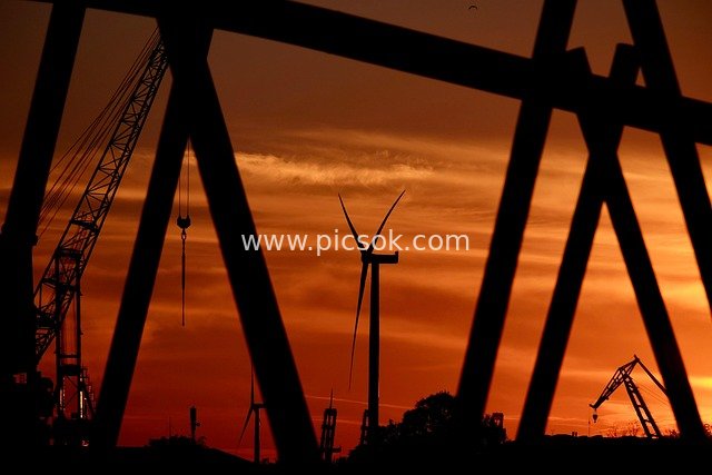 Industrial Sunset Scene: Silhouette Art of Wind Turbines and Cranes