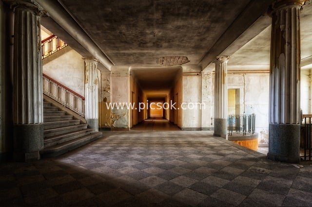 Abandoned Building Foyer with Columned Stairs – A Timeworn Retro Space