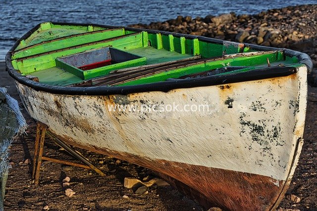 Weathered Old Wooden Fishing Boat Docked on Gravel Shore - Retro Restoration Scene