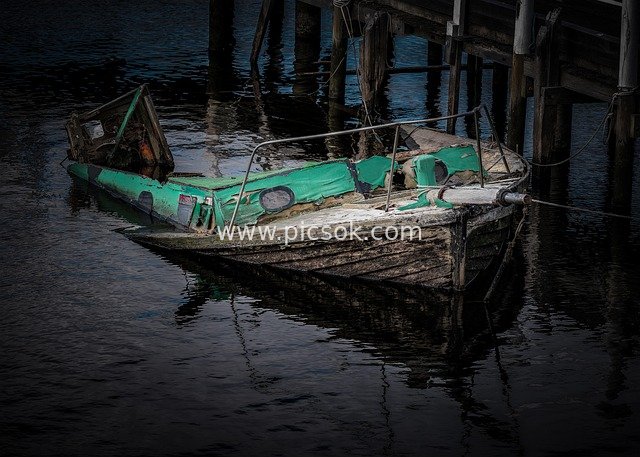Abandoned Rotting Wooden Boat by the Dock: Desolate Scene of a Dilapidated Vessel