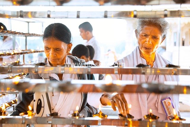 Elderly Women Lighting an Oil Lamp: A Moment of Traditional Life in Warm Light