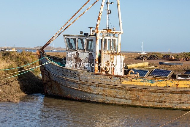 Old Fishing Boat Equipped with Solar Panels: A Working Scene of Old and New Intertwined by the Seaside