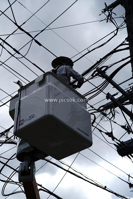 High-altitude Electric Power Maintenance Worker at Work: Cluttered Wires Fill the Sky