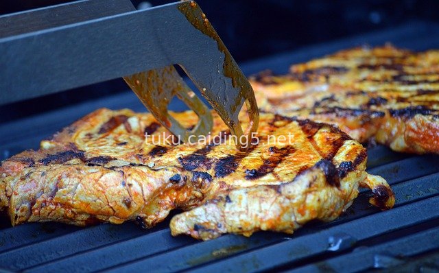 夏日烧烤季：烤架上的香煎牛排与烧烤钳