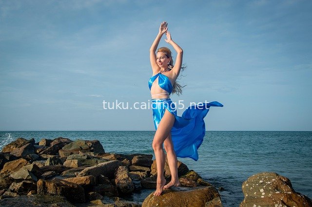 Fashion Beach Photoshoot of a Model in a Blue Dress on Seaside Rocks