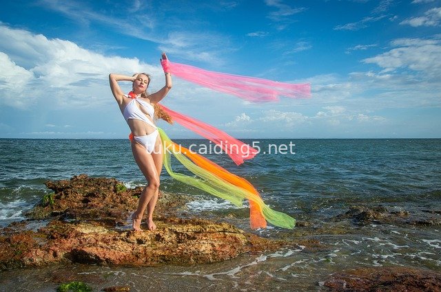Fashion Photoshoot of Bikini Model Dancing with Colorful Streamers by the Sea