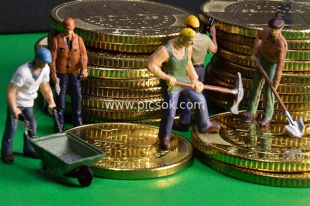 Creative Financial Wealth Scene with Mini Workers and Gold Coin Piles