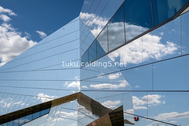 Modern Glass Building Reflecting Blue Sky and Fluffy White Clouds