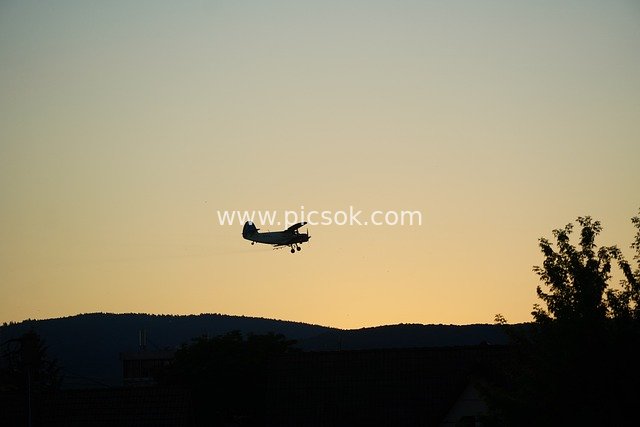 Airplane Silhouette in Flight at Dusk: Transport Scene Under Sky and Mountains