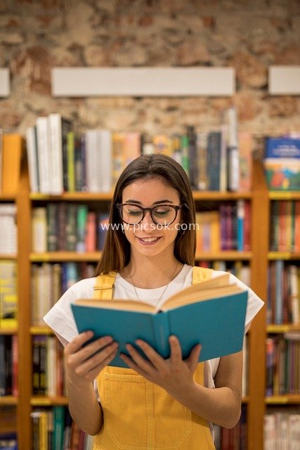 A Cozy Scene of a Girl Wearing Glasses Reading a Book in the Library