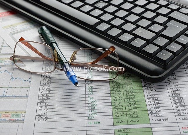Business Office Scene: Keyboard, Glasses, Pen and Financial Data Charts