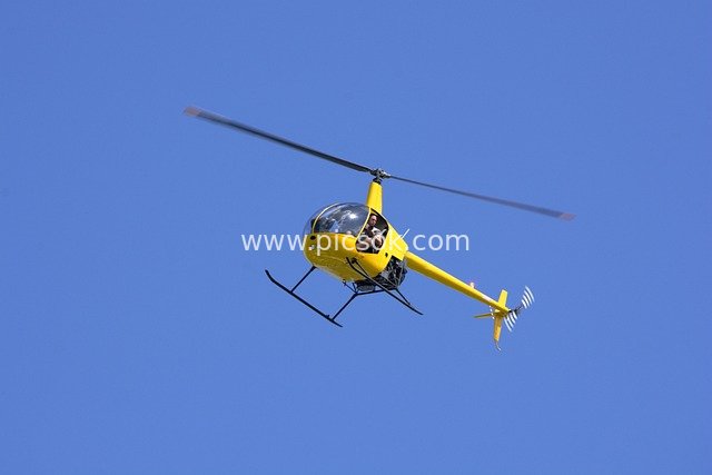 Small Yellow Helicopter Flying in Clear Blue Sky - Pilot Conducting Aerial Photography