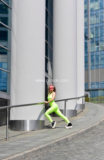Energetic Woman Stretching in Neon Green Sportswear in Modern City