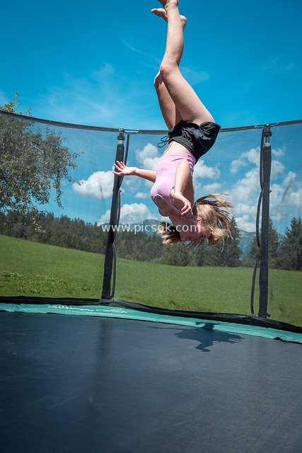 Girl Doing Handstand Jump on Outdoor Trampoline - Vibrant Sports Scene