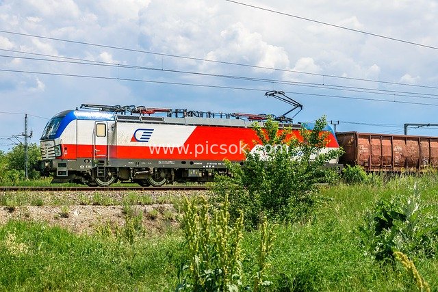 Electric Freight Locomotive Traveling on Rural Railway Amid Natural Scenery