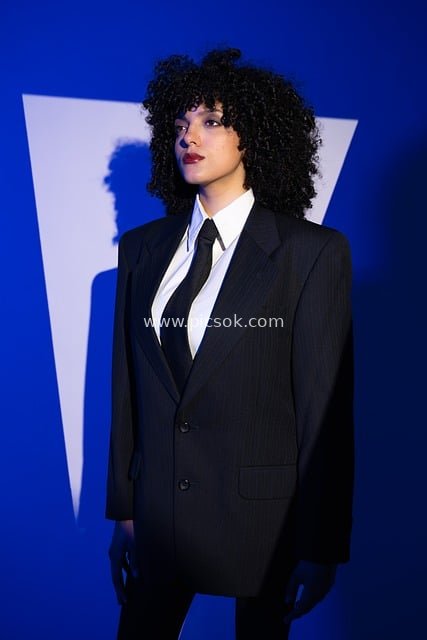 Female Model in Black Pinstripe Suit with Curly Hair - Fashion Portrait on Blue Background