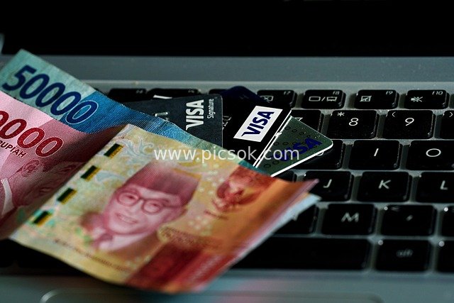 Indonesian Rupiah Cash and Credit Cards Placed on Laptop Keyboard