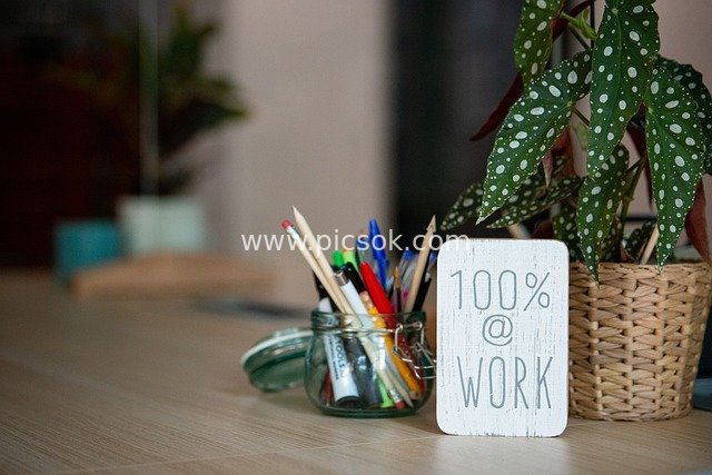 Home Office Desk with 100%@WORK Motivational Sign and Greenery Decoration
