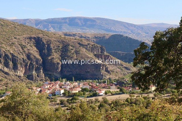 Valley Village with Red Roofs and Layered Mountain Landscape