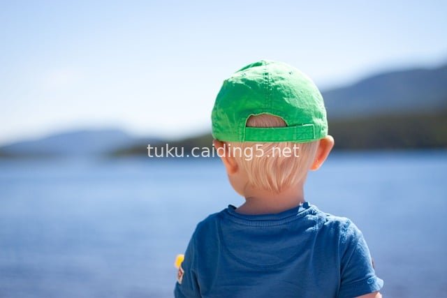 Back View of a Little Boy Wearing a Green Cap by the Lake in Summer - Sunny Playful Scene