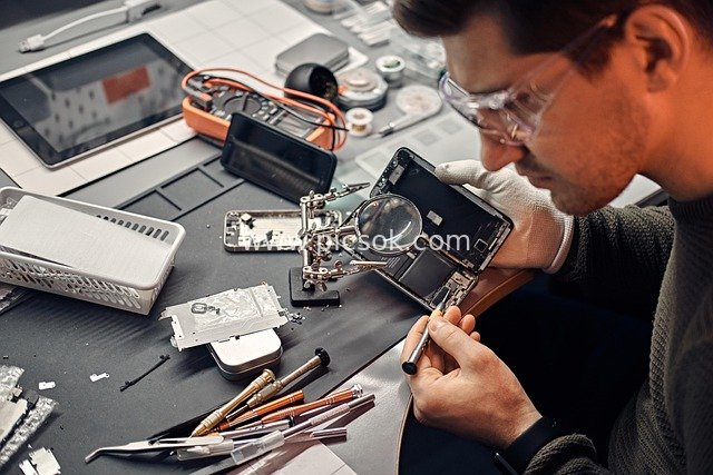 专业技术员用放大镜修复损坏智能手机的细节