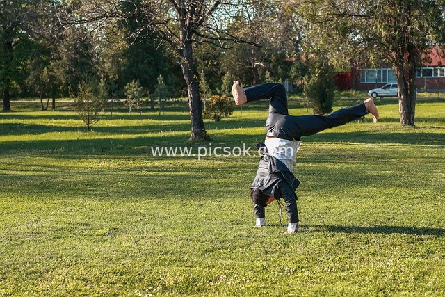 Vibrant Moment: Young Man Doing a Handstand on Park Lawn
