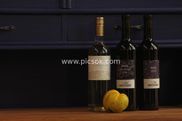 Still Life of Three Wine Bottles and Yellow Peaches on a Wooden Countertop
