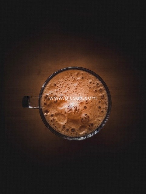 Warm Brown Coffee in a Glass with Foam Latte Art Against a Dark Background