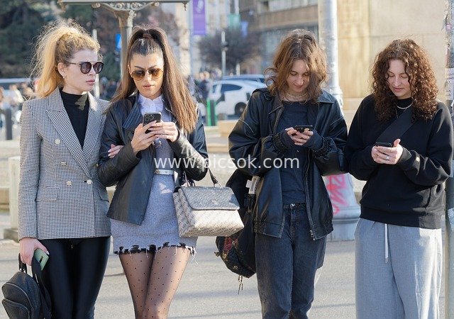 Daily Scene of Casual Women Engrossed in Phones on Urban Streets