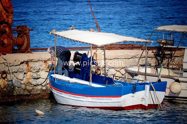 Blue-and-White Fishing Boat and Fisherman Working by the Sea in Naxos, Greece