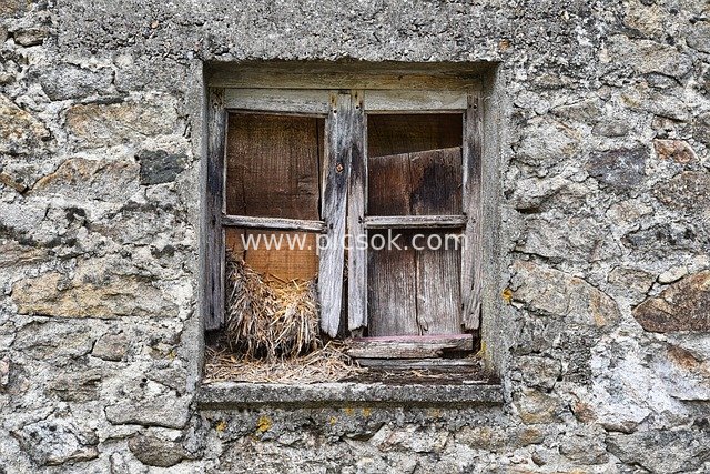 Dilapidated Wooden Window of an Abandoned Stone House: Weathered Window of a Time-Worn Old Building