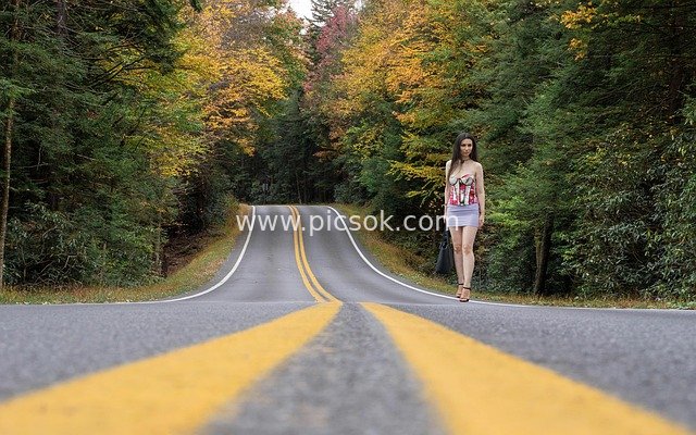 Beautiful Autumn Landscape with a Young Woman by a Forest Road