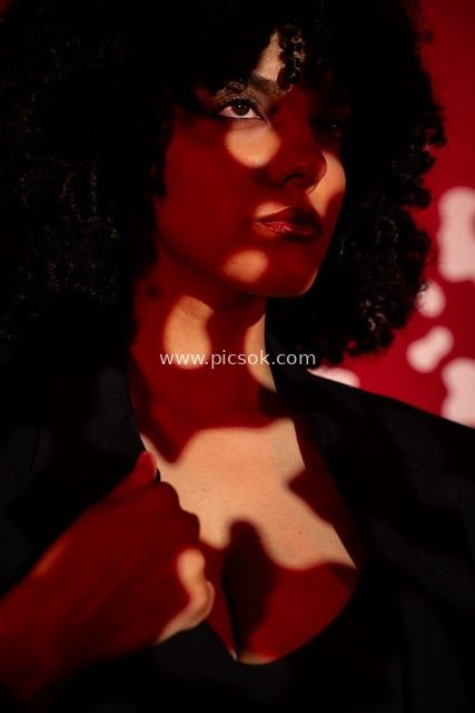Fashion Female Portrait with Light-and-Shadow Art, Red Background, and Black Curly Hair