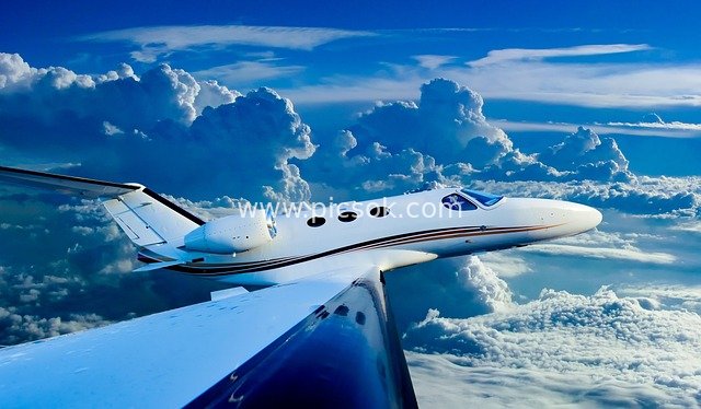 White Private Jet Soaring in Clear Blue Sky – Magnificent Flight Scene Among Cumulus Clouds