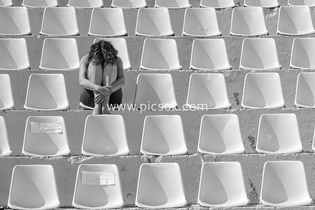 Lonely Woman Curled Up on Seats in an Abandoned Auditorium, Lost in Thought