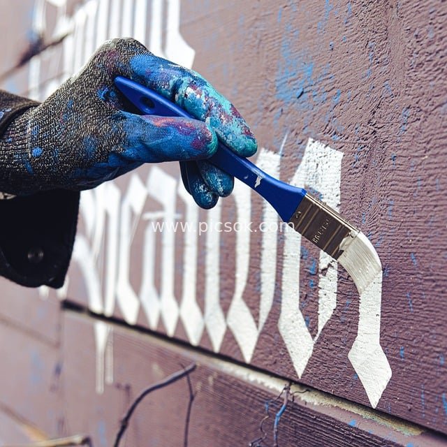 街头艺术家手绘白色书法 蓝漆画笔创作木质墙