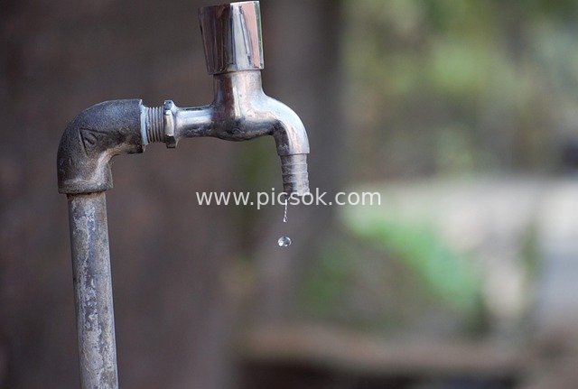 Close-up of a Dripping Old Public Faucet and Outdoor Water Supply Pipe